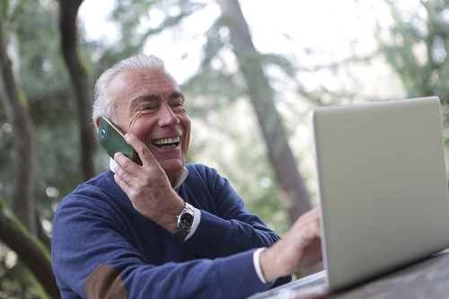 man-on-phone-smiling-at-computer-free-video-content-for-real-estate-Reazo-leads