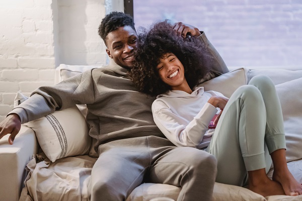 couple-cuddling-on-couch-smiling-receiving-affordable-housing-Reazo-real-estate