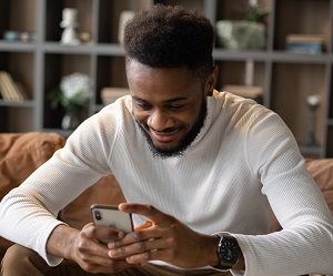 man-smiling-at-phone-engaging-leads-through-texting