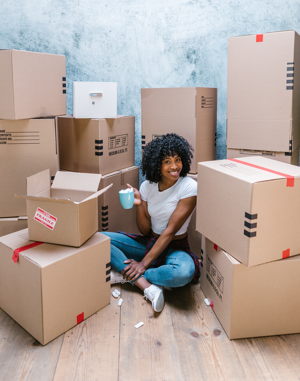 happy-woman-sitting-with-moving-boxes-Reazo-real-estate